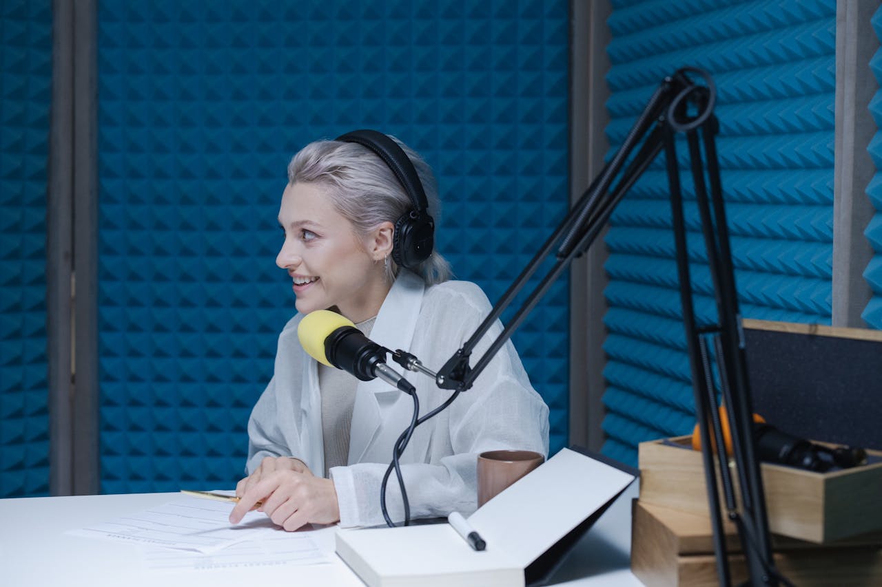 contact-img Woman wearing headphones recording a podcast in a soundproof studio with a microphone.